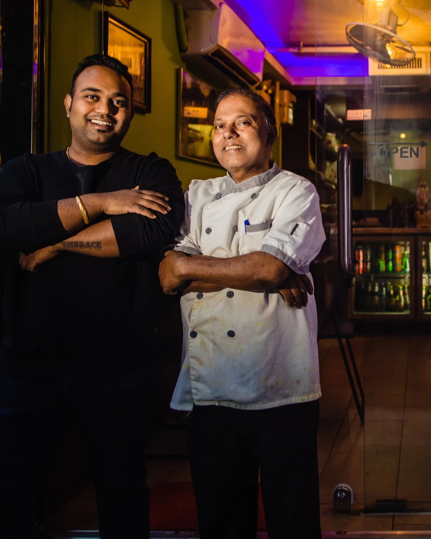 Monu Gomes in chef whites and Alex Gomes standing in the doorway of the restaurant
