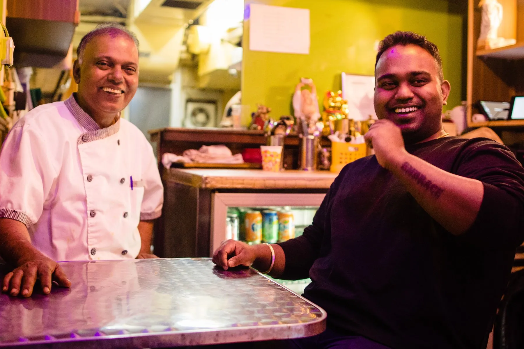 Monu and Alex Gomes seated at a table in the restaurant, both laughing