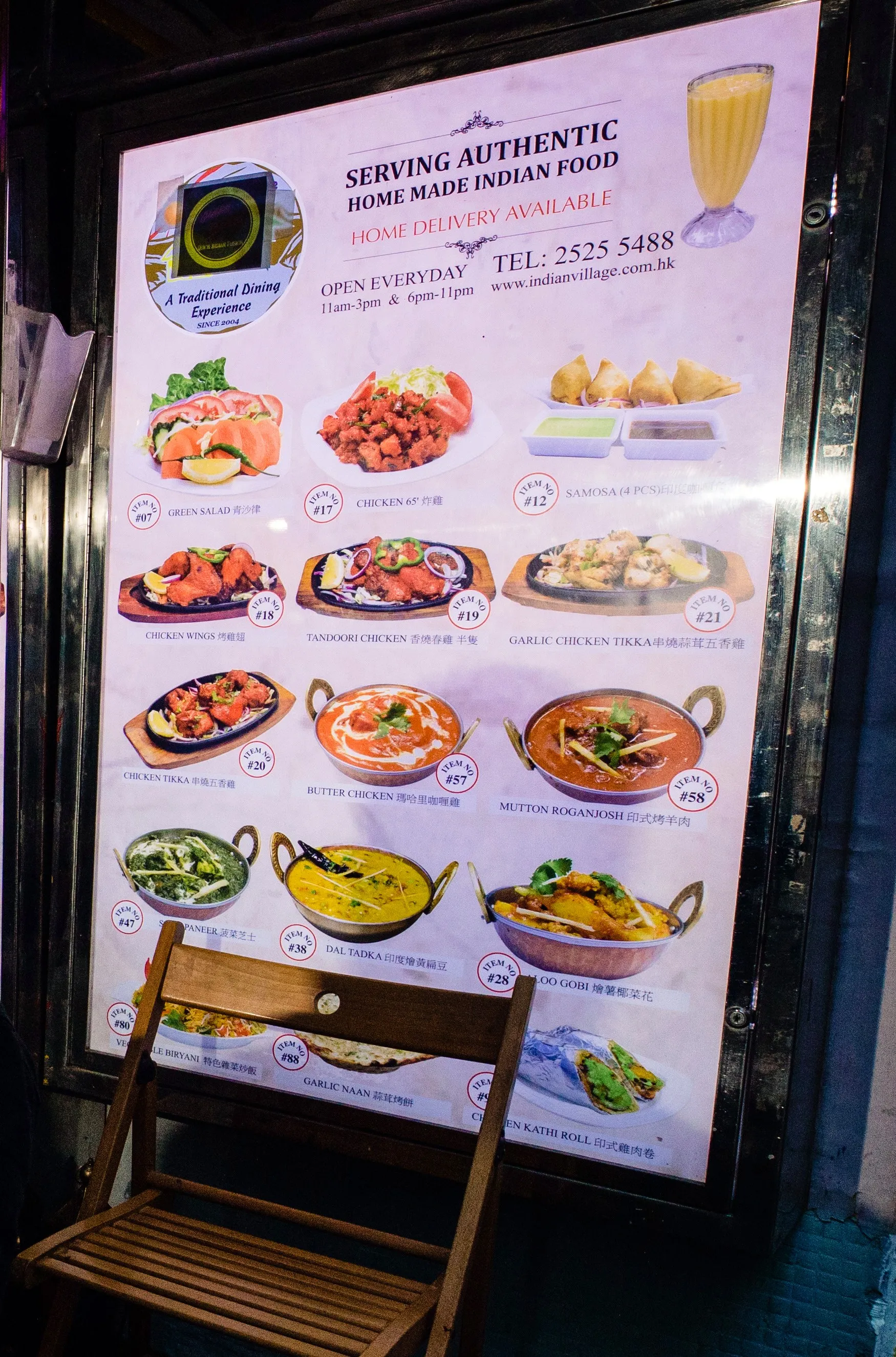 The illuminated Indian Village menu board outside the restaurant, its roundel reading A Traditional Dining Experience, since 2004