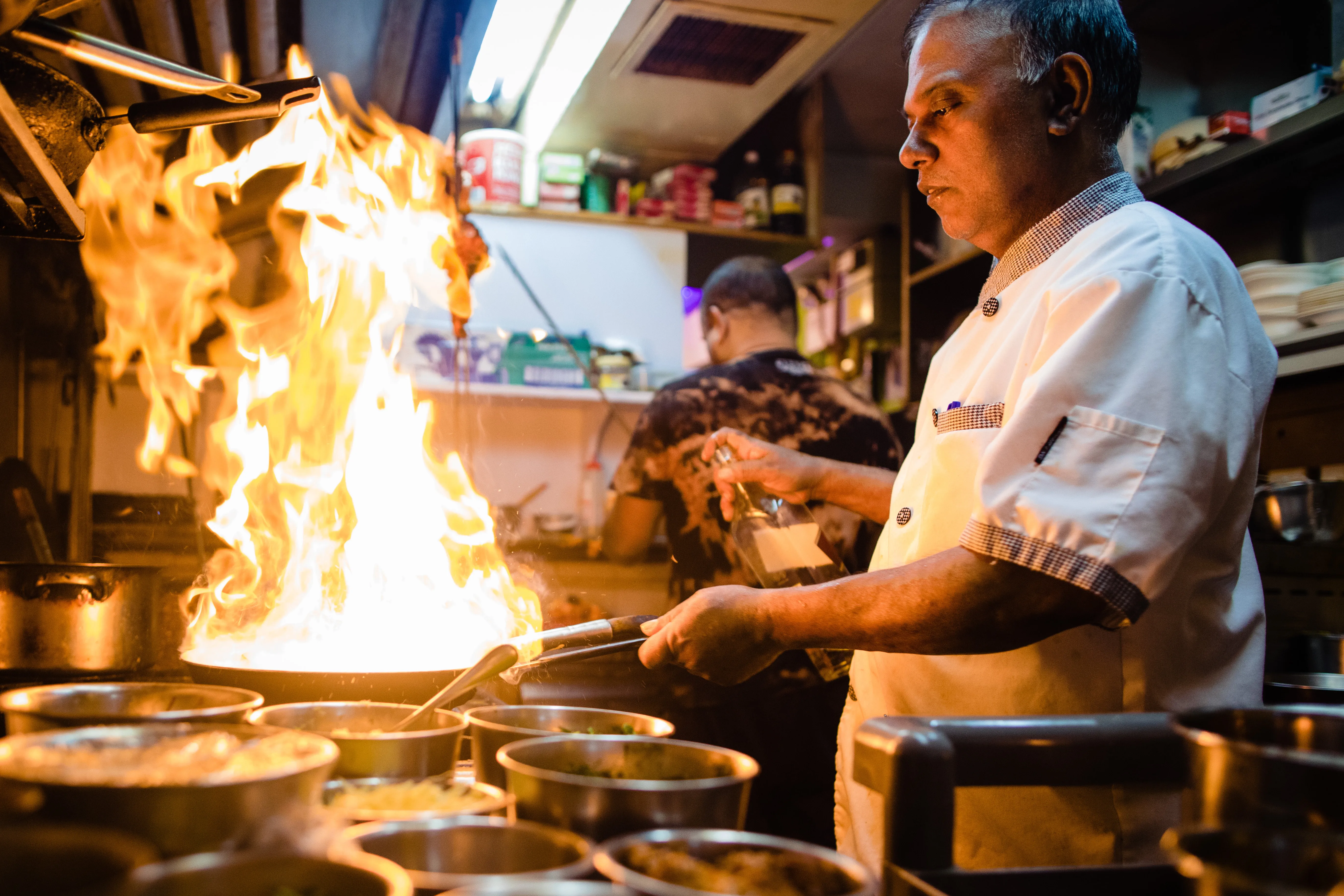 Monu Gomes at the pass, flames rising from the pan